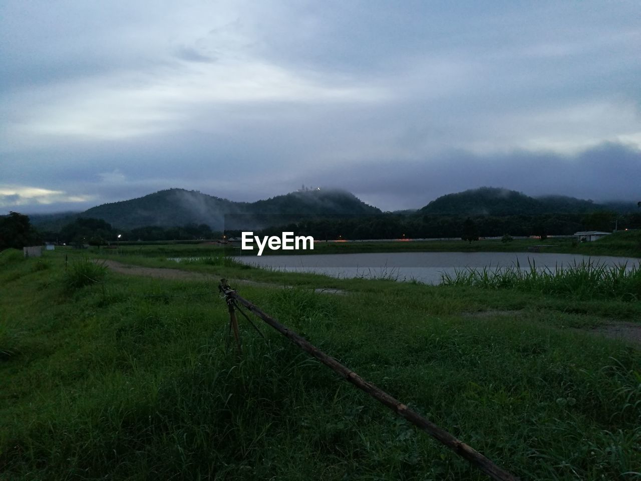 Scenic view of field by lake against sky