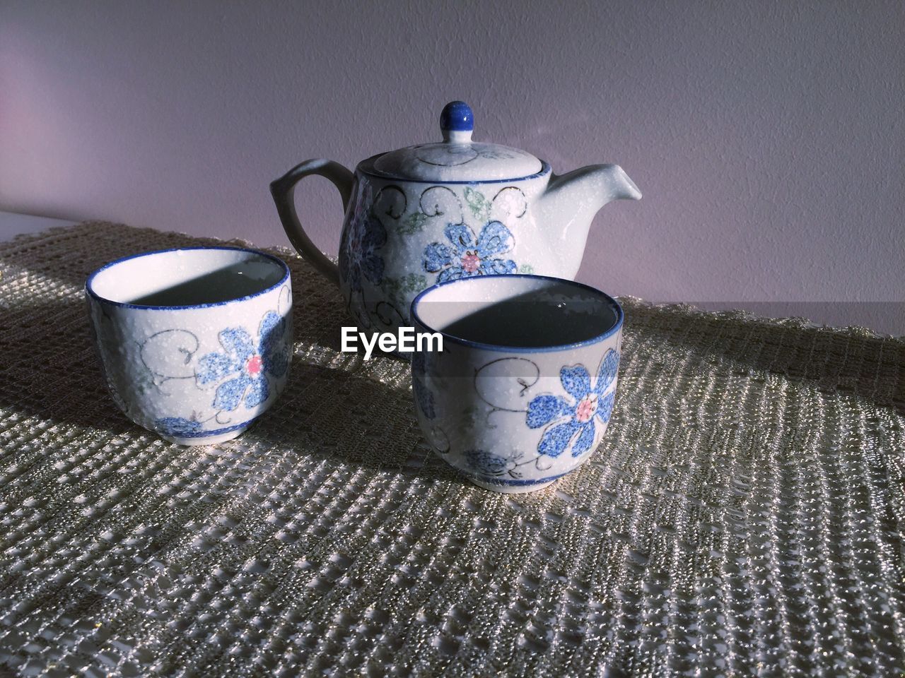 High angle view of floral pattern teapot and cups on table
