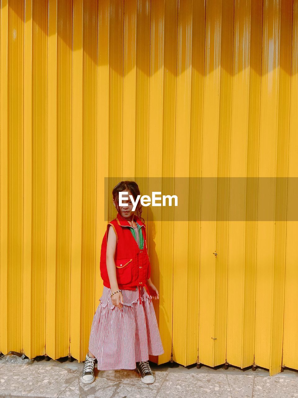 Portrait of a smiling girl standing against yellow wall