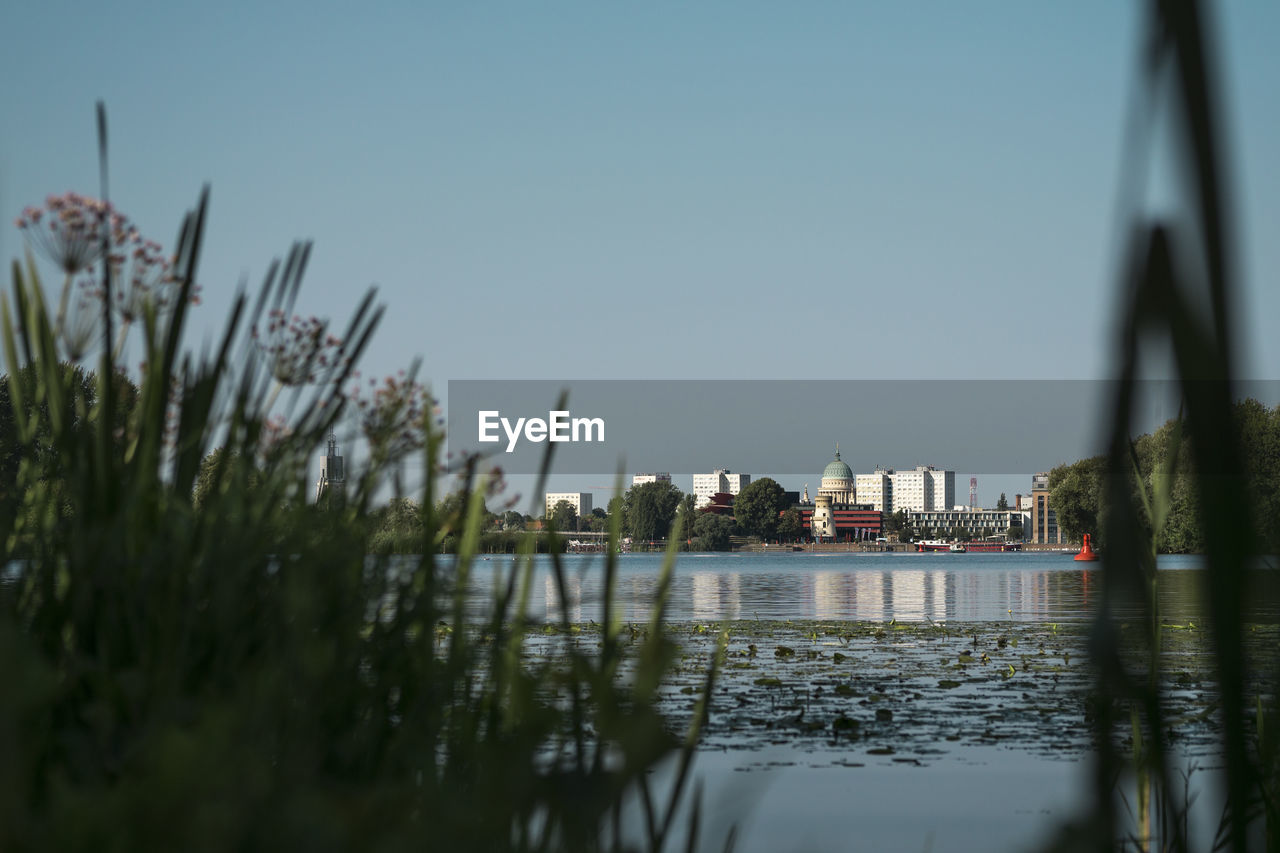 Scenic view of river by buildings against clear sky