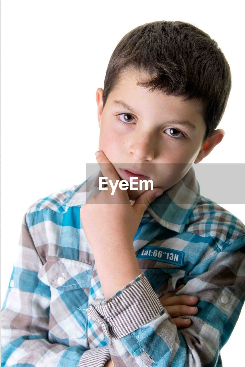 Portrait of boy with hand on chin against white background