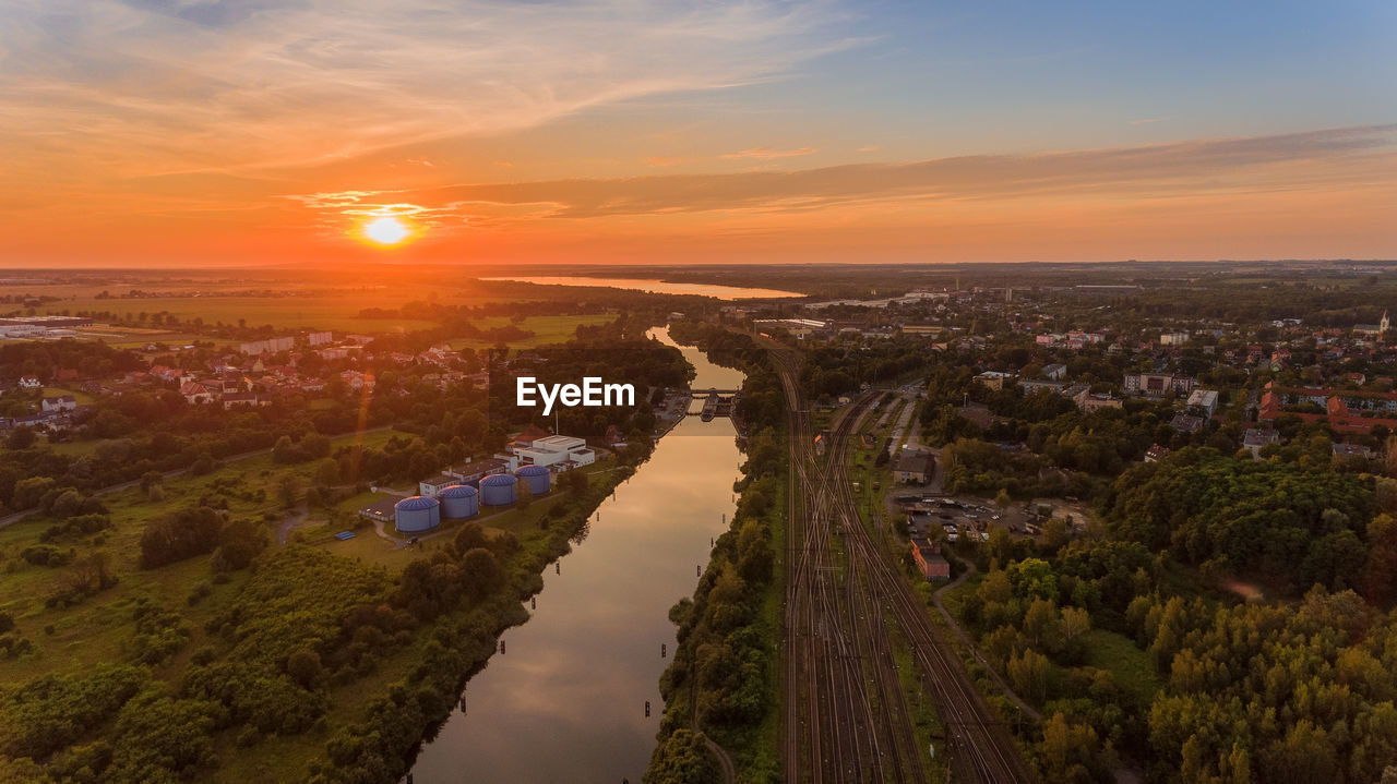 High angle view of river amidst buildings against sky during sunset