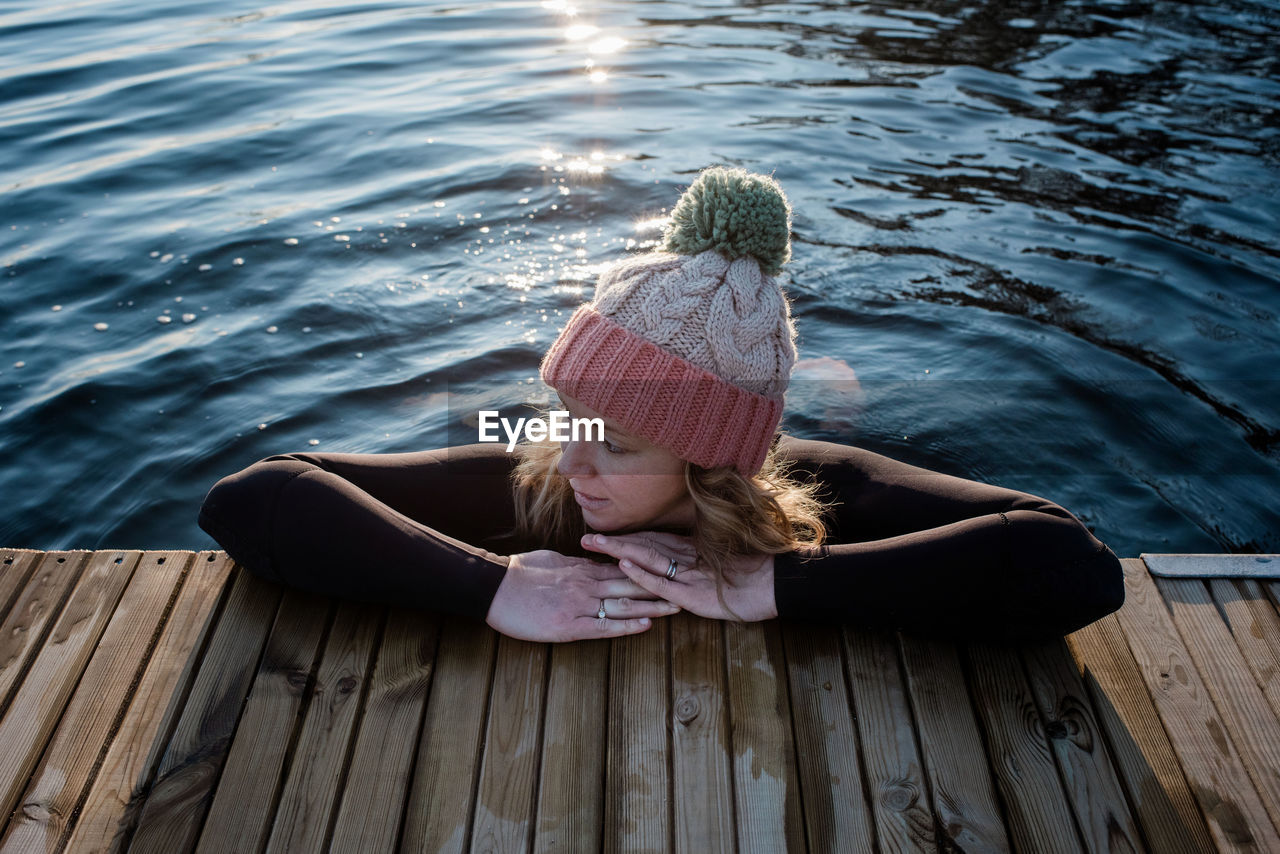 Woman leaning on a pier whilst in the water cold water swimming