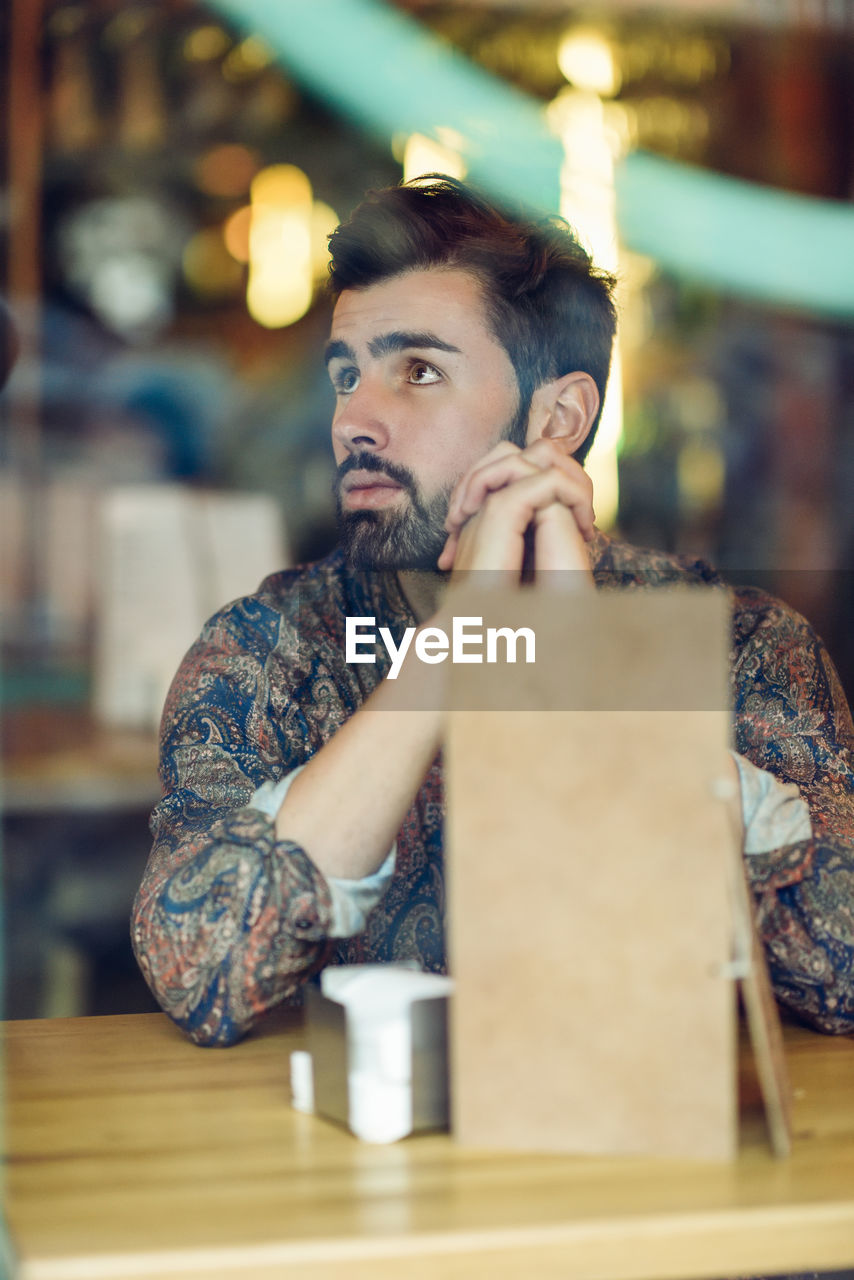 Thoughtful man sitting at table in restaurant