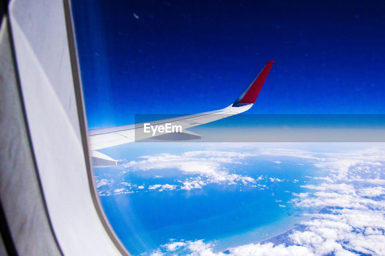 AERIAL VIEW OF AIRPLANE WING OVER LANDSCAPE SEEN FROM WINDOW