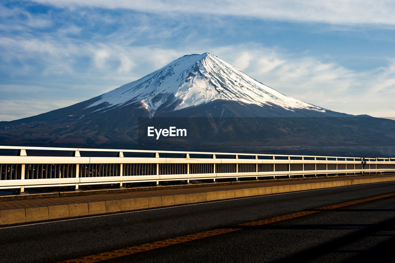 Road leading towards snowcapped mountains against sky