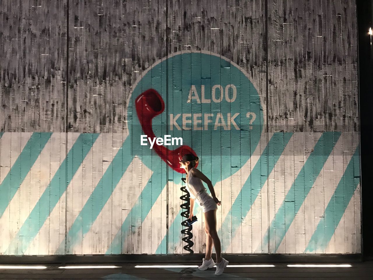 Full length side view of woman standing by wall in city at night