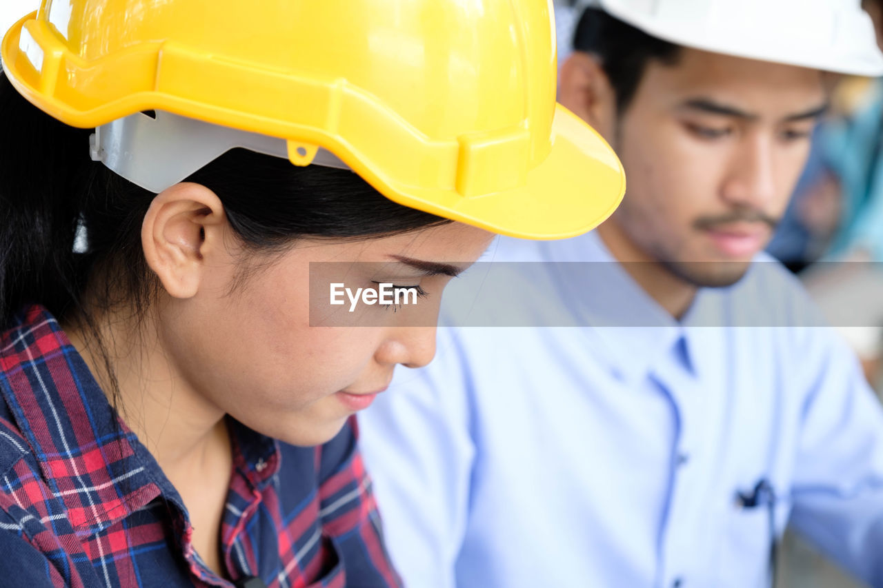 Business people wearing hardhats while looking down in office