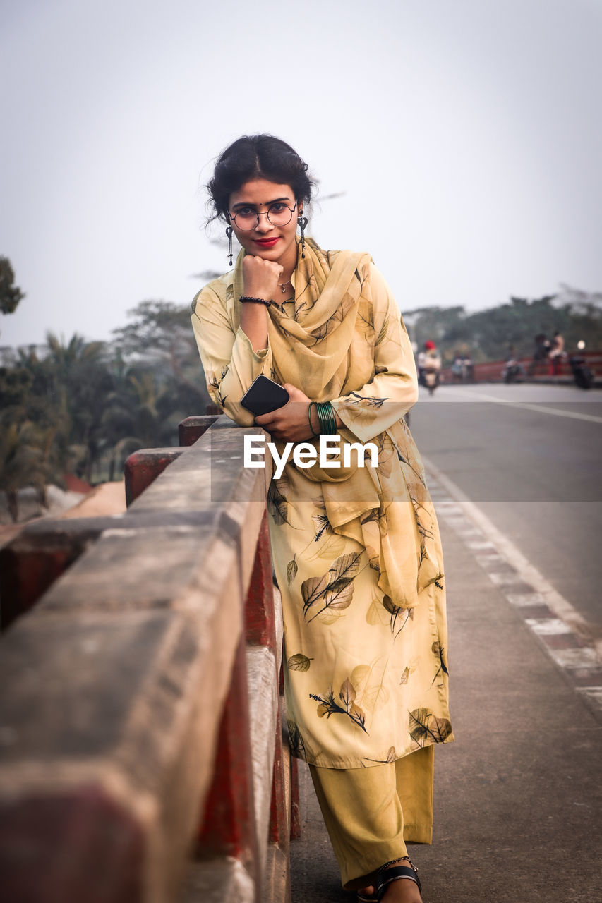 Portrait of young woman standing on road