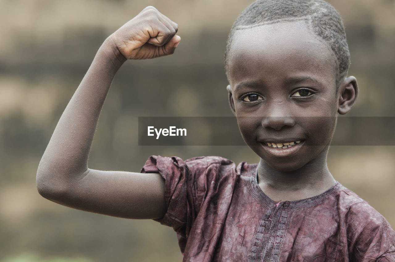 Portrait of smiling boy showing bicep