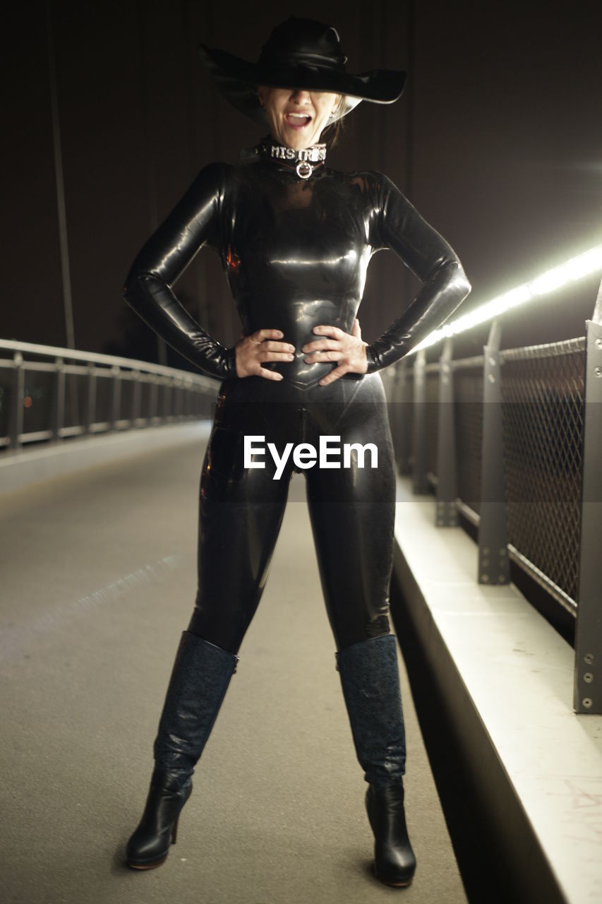 PORTRAIT OF YOUNG WOMAN STANDING AGAINST RAILING