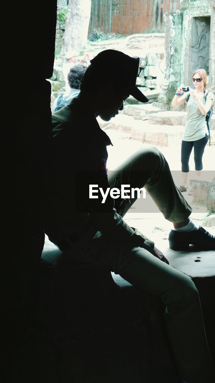 SIDE VIEW OF YOUNG WOMAN SITTING ON BENCH