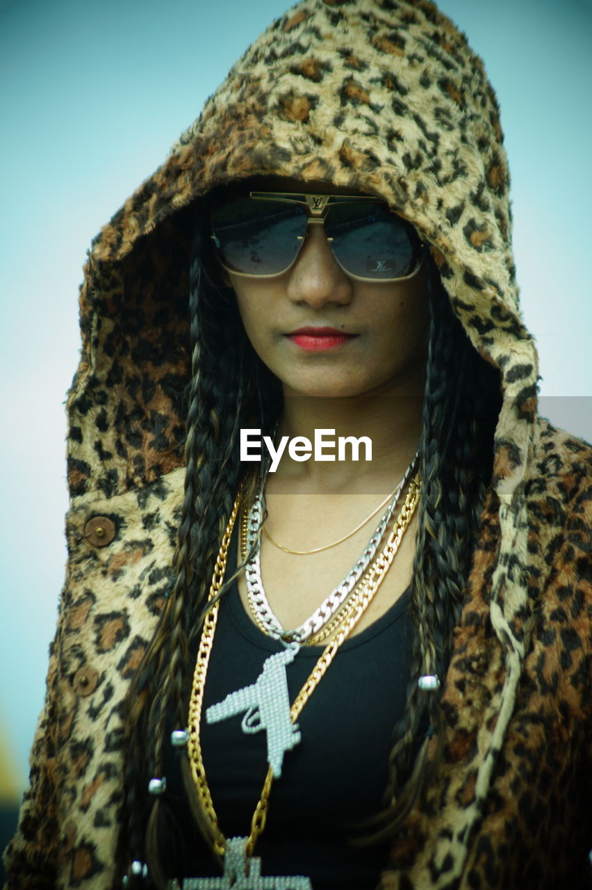 PORTRAIT OF YOUNG WOMAN WEARING SUNGLASSES OUTDOORS