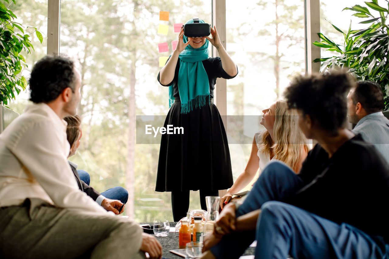 Businesswoman smiling while wearing virtual reality simulator during conference with colleagues at convention center