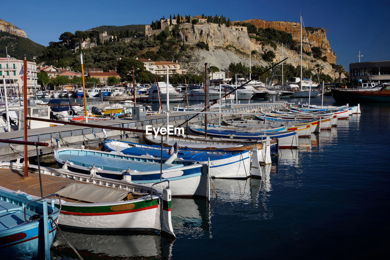 SAILBOATS MOORED AT HARBOR