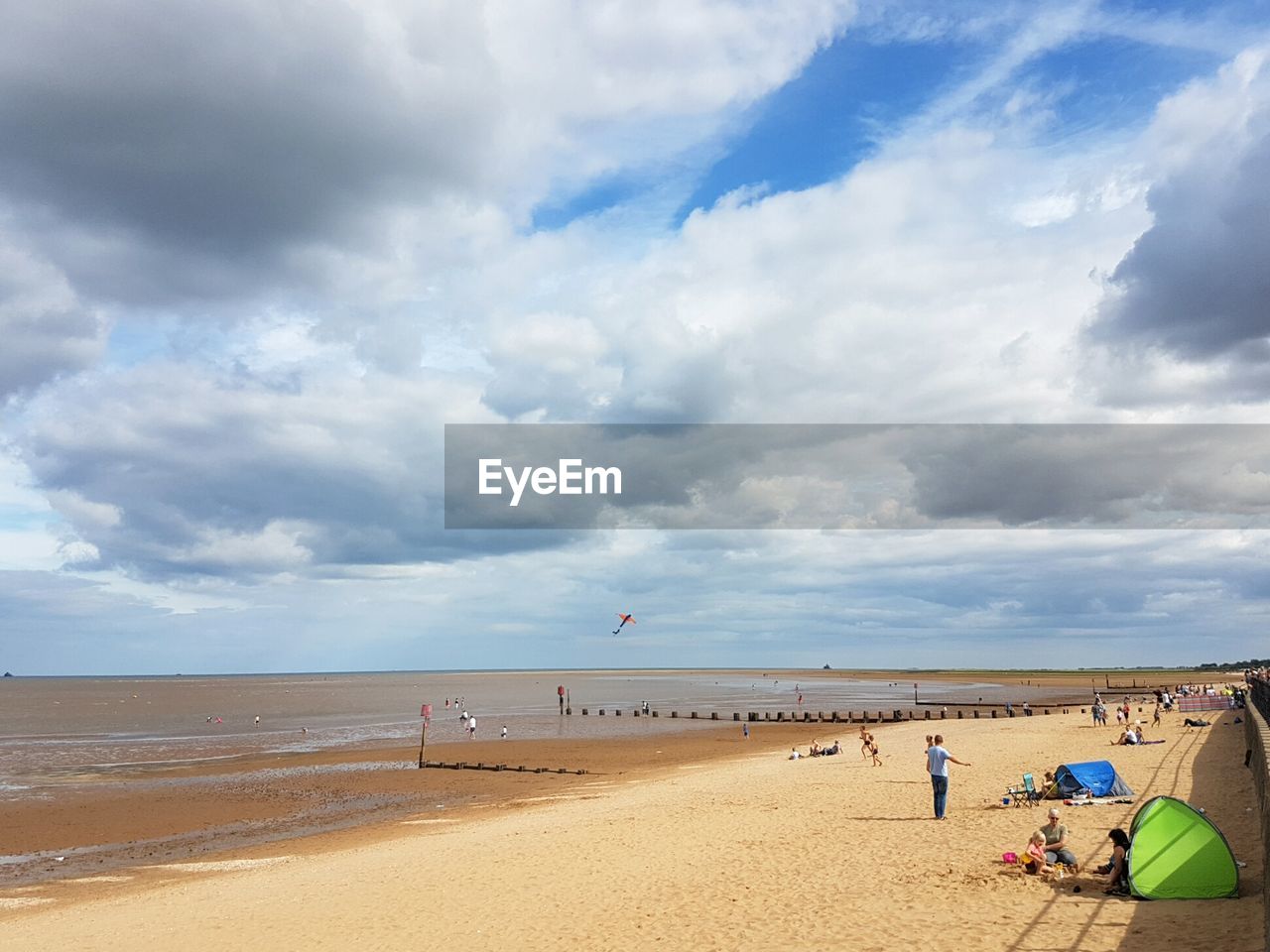 People at beach against cloudy sky