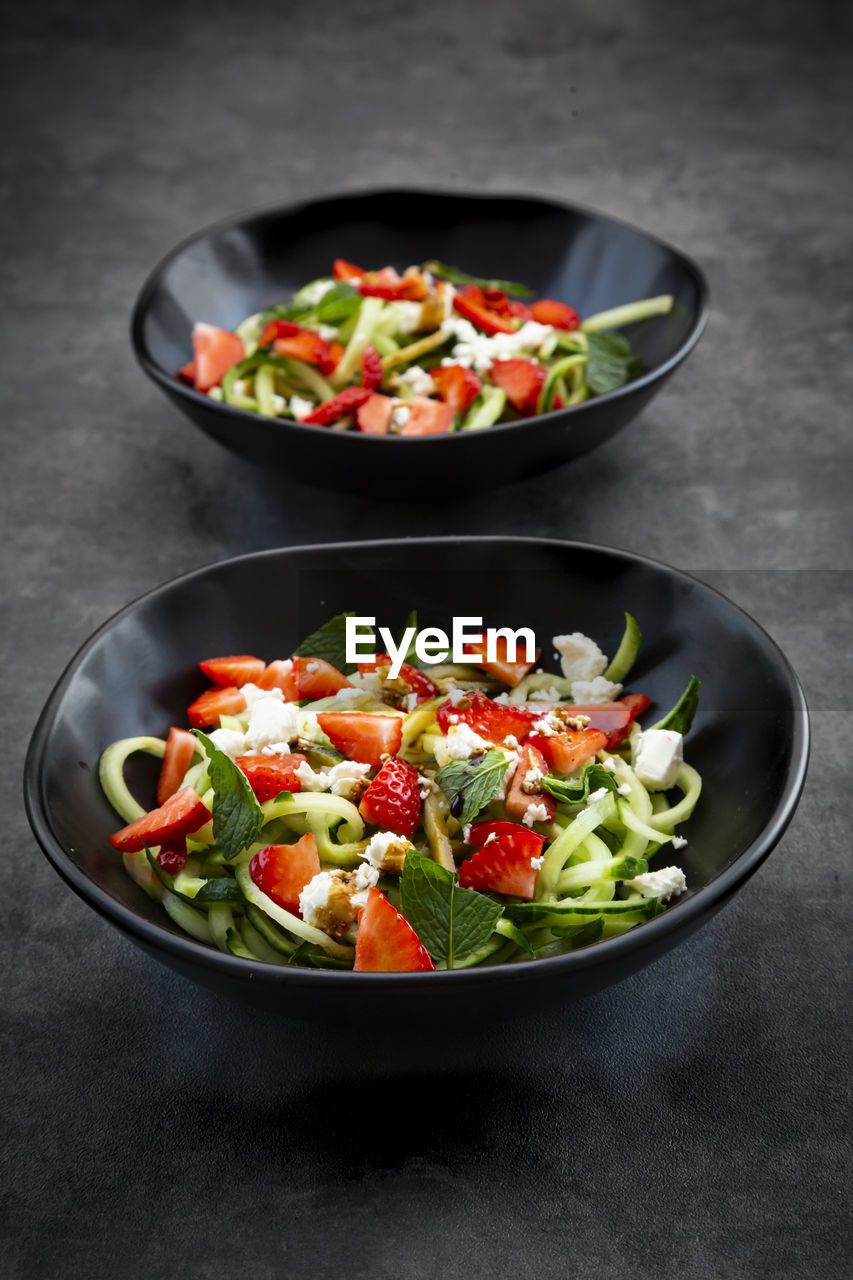 Two bowls of strawberry cucumber salad with feta, mint and balsamico vinegar