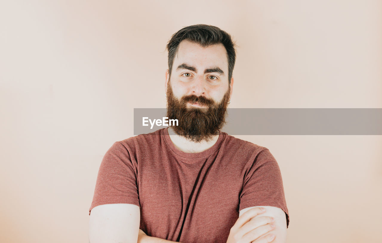 beard, facial hair, one person, portrait, adult, men, indoors, looking at camera, casual clothing, front view, moustache, person, studio shot, human hair, copy space, waist up, hairstyle, smiling, lifestyles, emotion, brown hair, young adult, hipster, clothing, human face, standing, happiness, looking, individuality, headshot