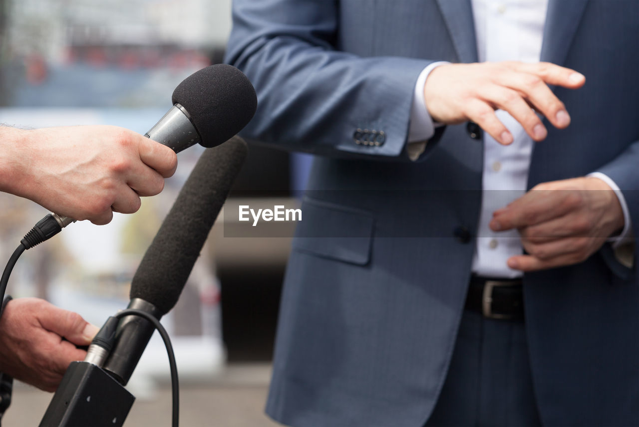 Cropped hands of journalists interviewing businessman