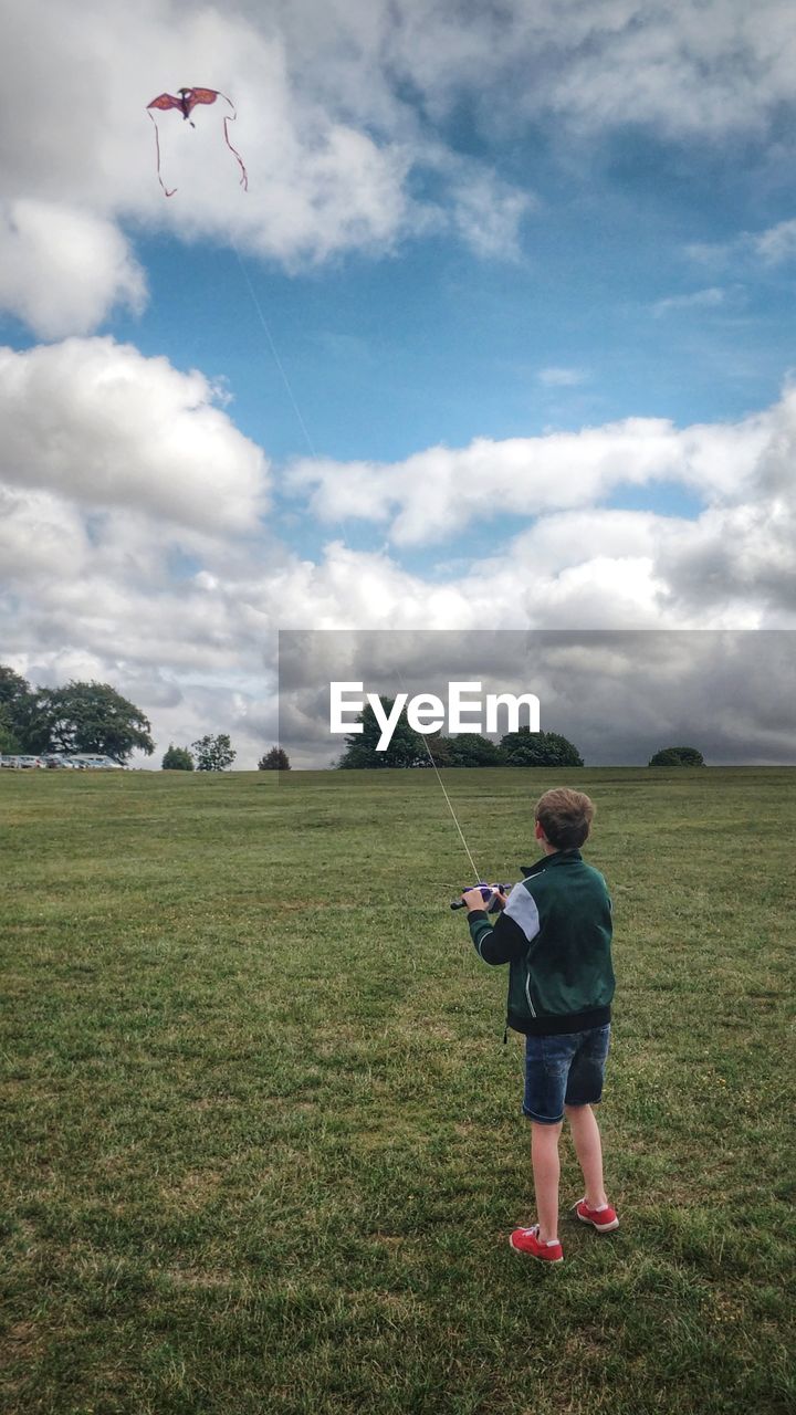 FULL LENGTH OF BOY FLYING OVER FIELD