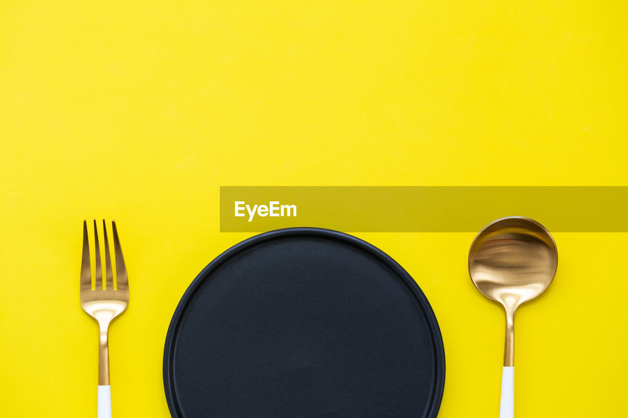 DIRECTLY ABOVE SHOT OF SPOON AND YELLOW TABLE
