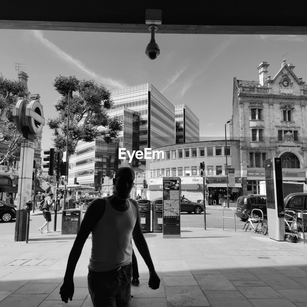 FULL LENGTH REAR VIEW OF MAN STANDING ON STREET AGAINST BUILDINGS IN CITY