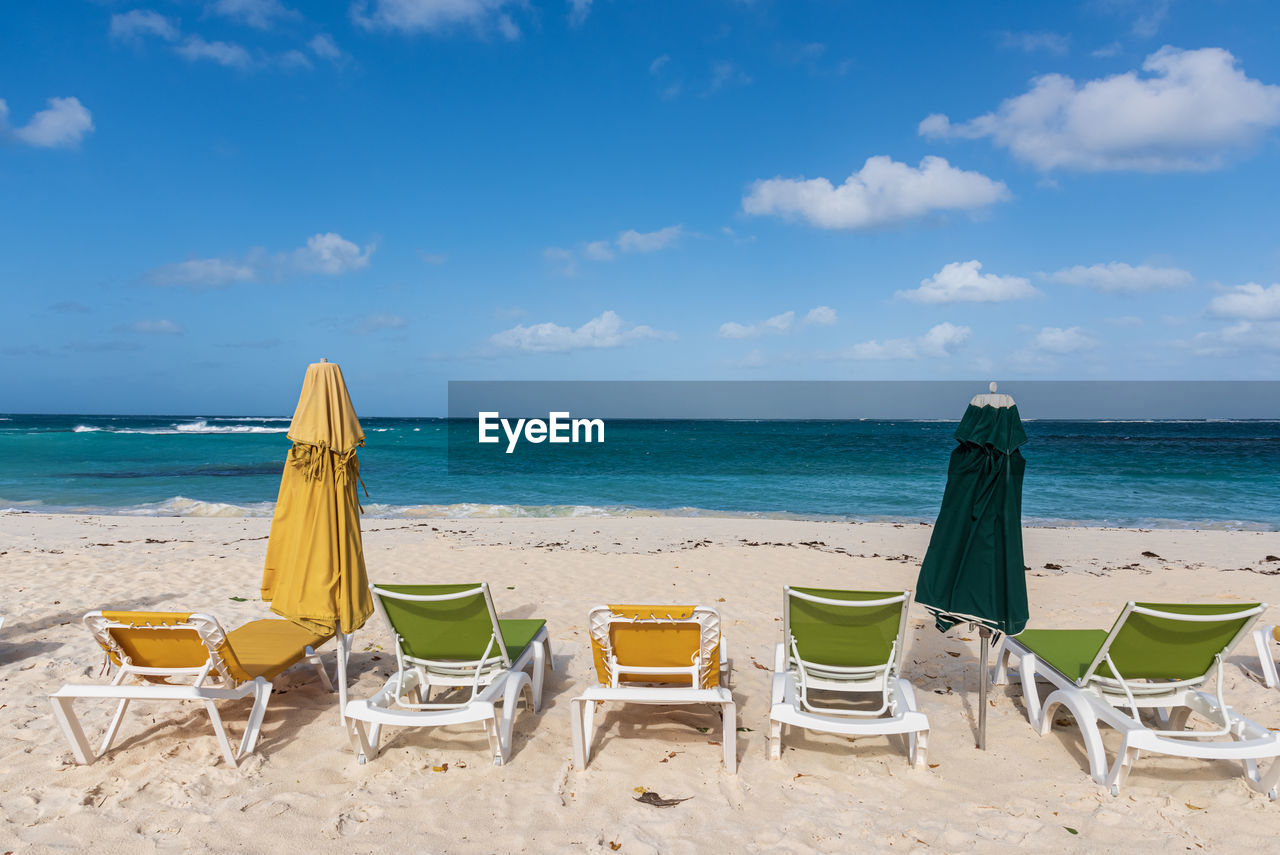 Chairs on beach against sky