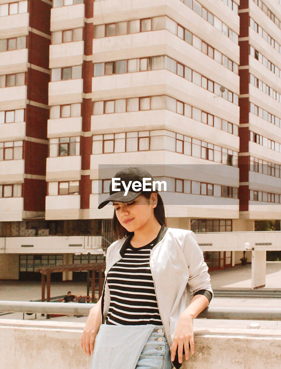 MID ADULT WOMAN STANDING AGAINST BUILDINGS IN CITY