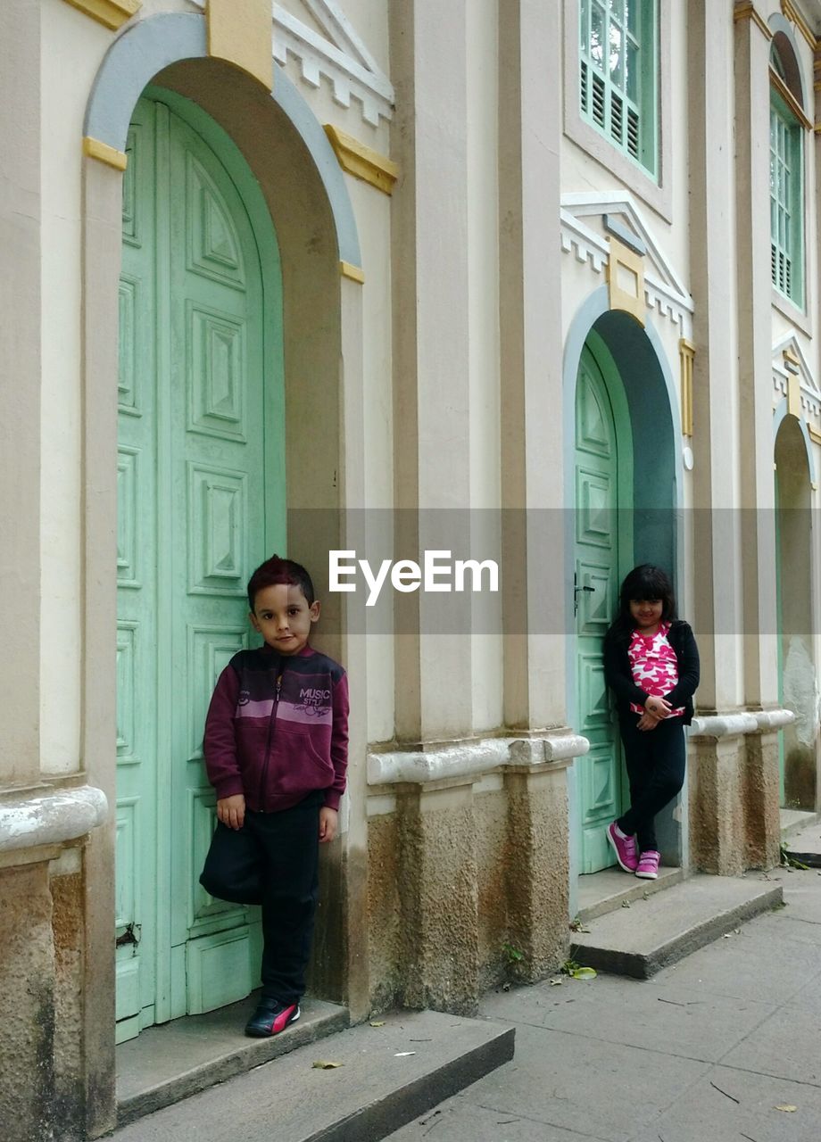 Portrait of siblings standing at doorway