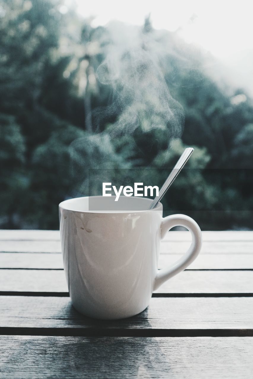 Close-up of steam emitting from coffee cup on table