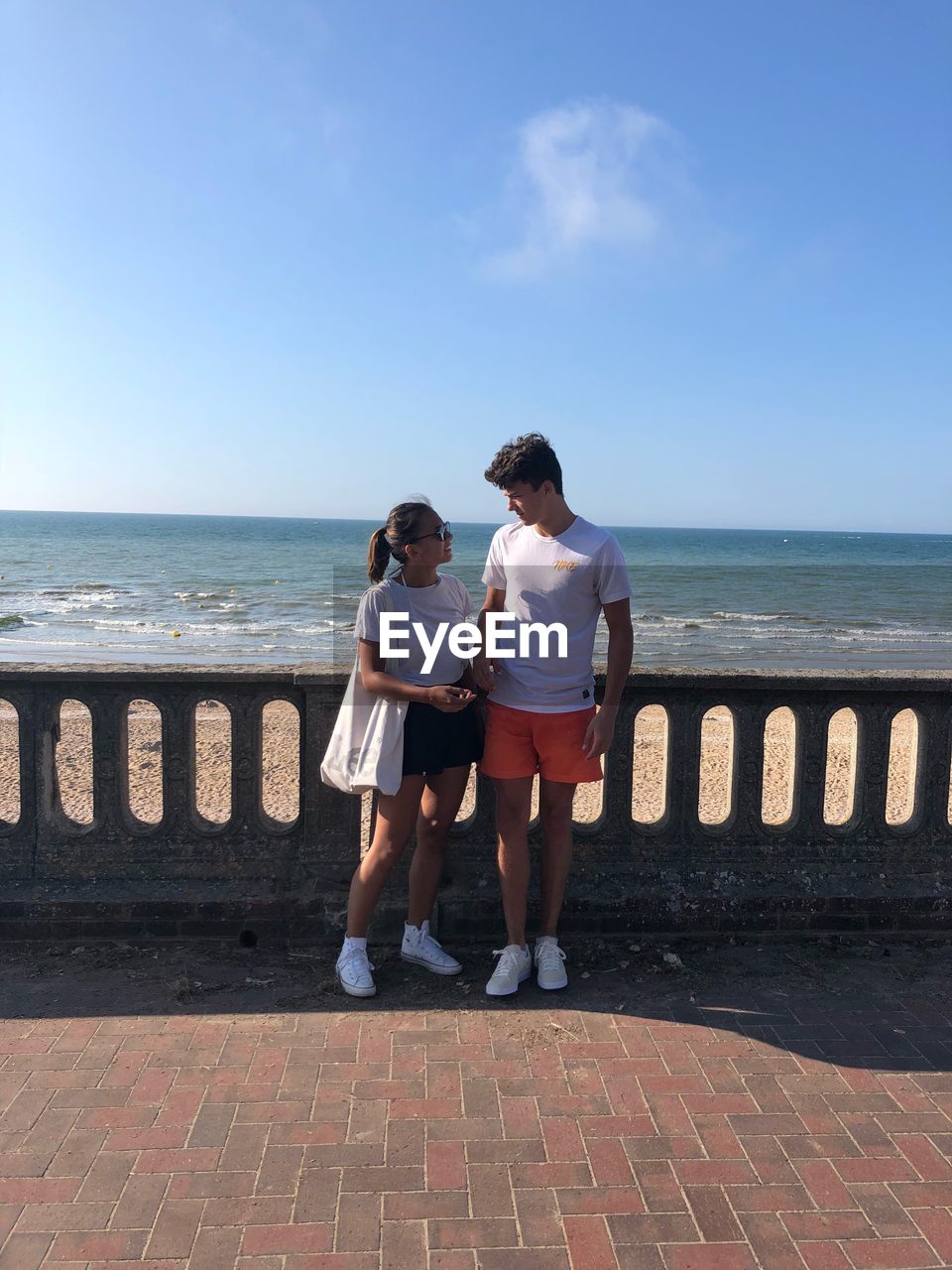 Couple standing by railing against sea 