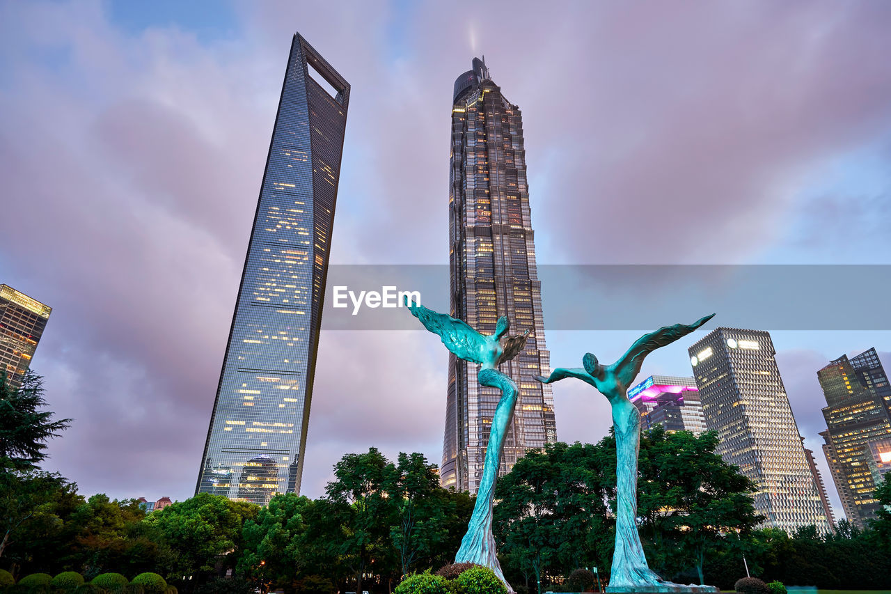 Low angle view of skyscrapers against cloudy sky