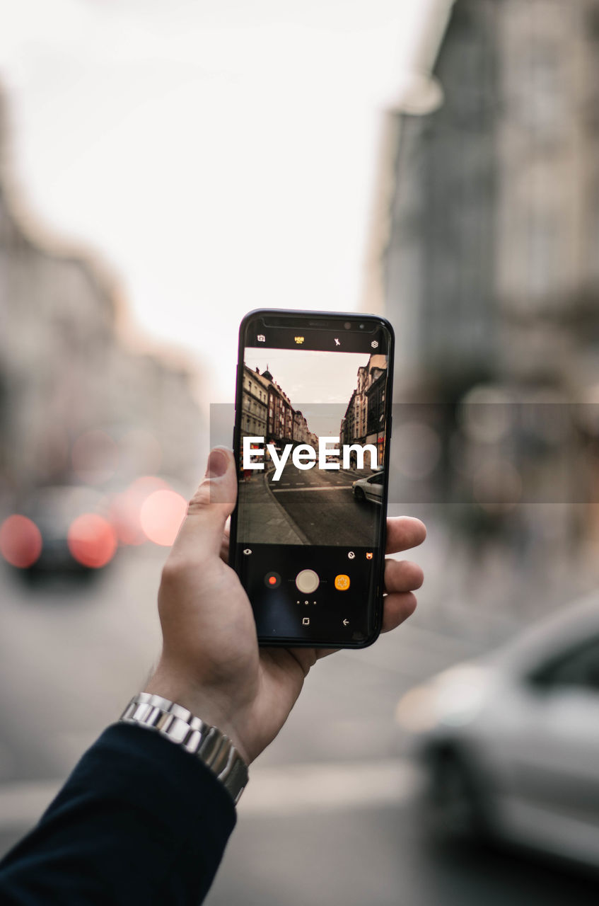 Cropped hand of woman photographing while in city