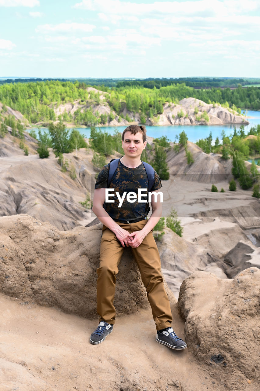 An adult male tourist with a backpack high mountains in an open area.