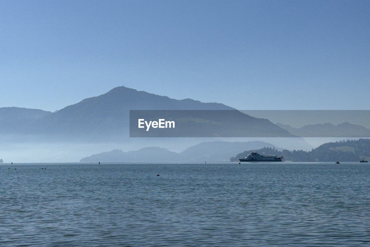 water, mountain, horizon, sea, scenics - nature, sky, beauty in nature, nature, blue, ocean, no people, tranquility, tranquil scene, bay, body of water, mountain range, travel, environment, land, landscape, travel destinations, coast, outdoors, clear sky, day, vehicle, non-urban scene, shore, tourism, copy space, idyllic