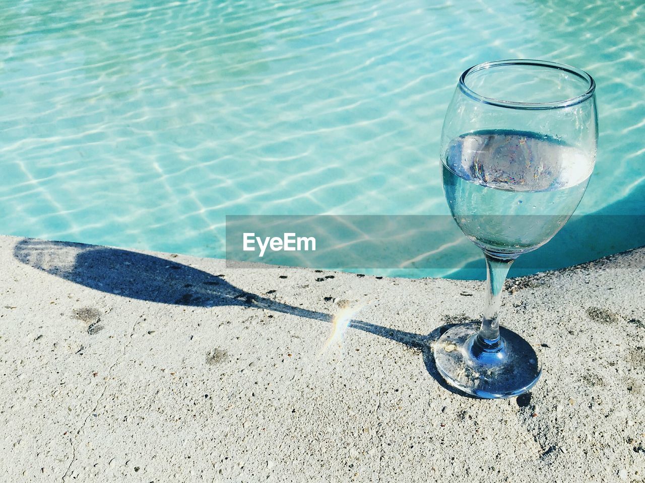 Close-up of drinking water in wineglass at poolside on sunny day