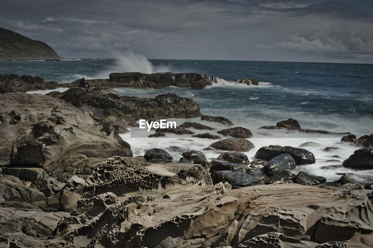 Scenic view of rocks in sea against sky