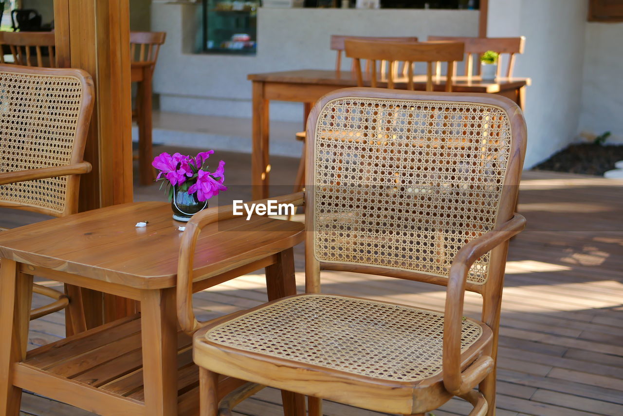 EMPTY CHAIRS AND TABLE BY POTTED PLANTS