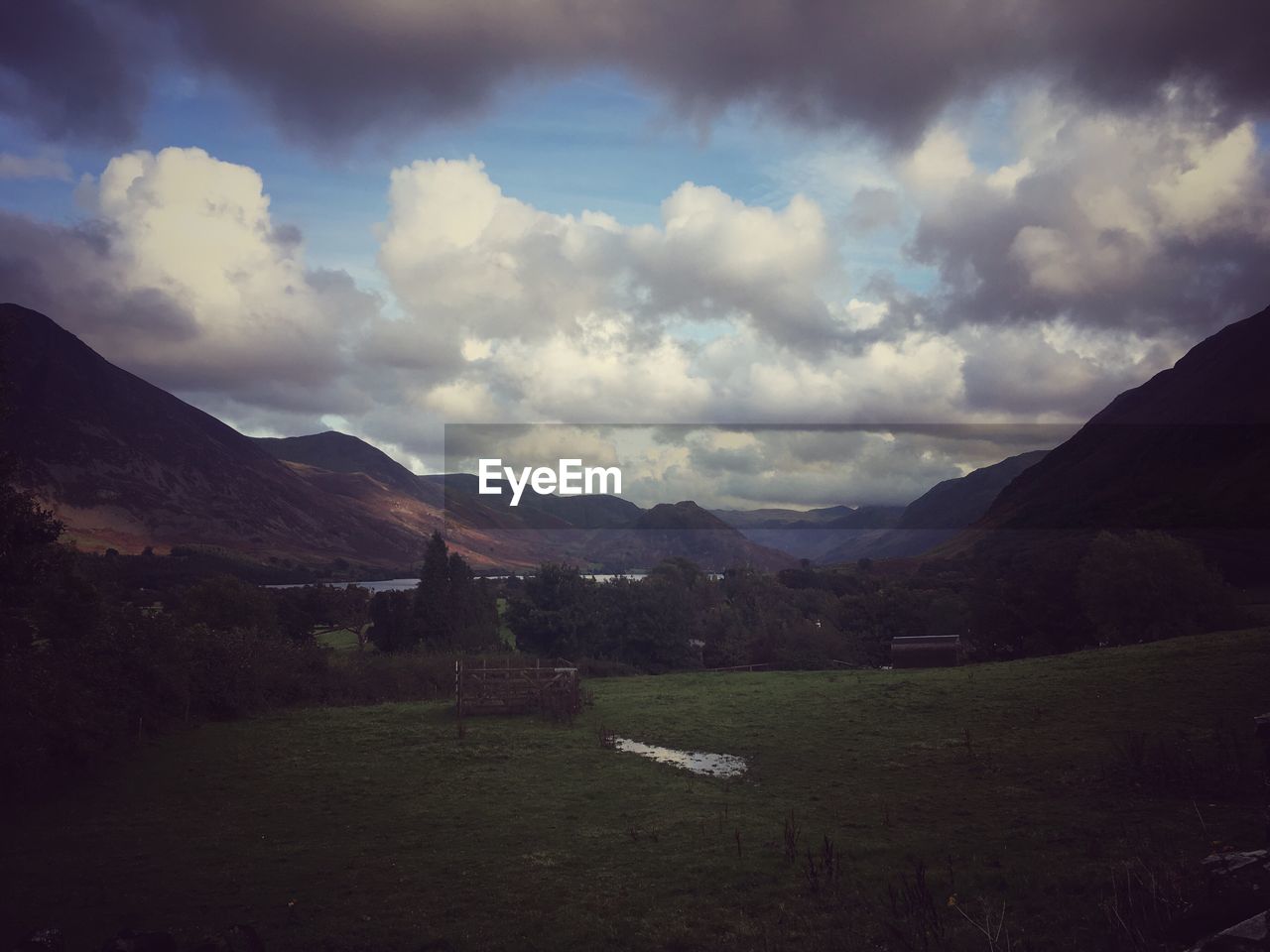 COUNTRYSIDE LANDSCAPE AGAINST MOUNTAIN RANGE