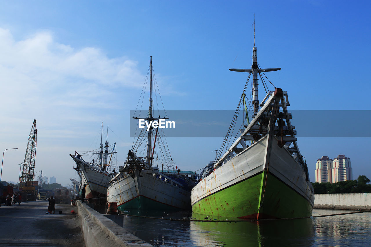 Sailboats moored at harbor against sky