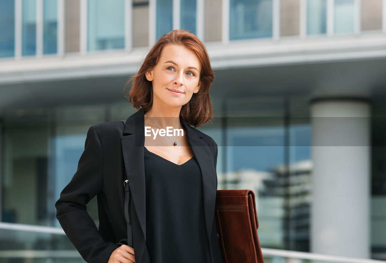 portrait of young businesswoman standing against building