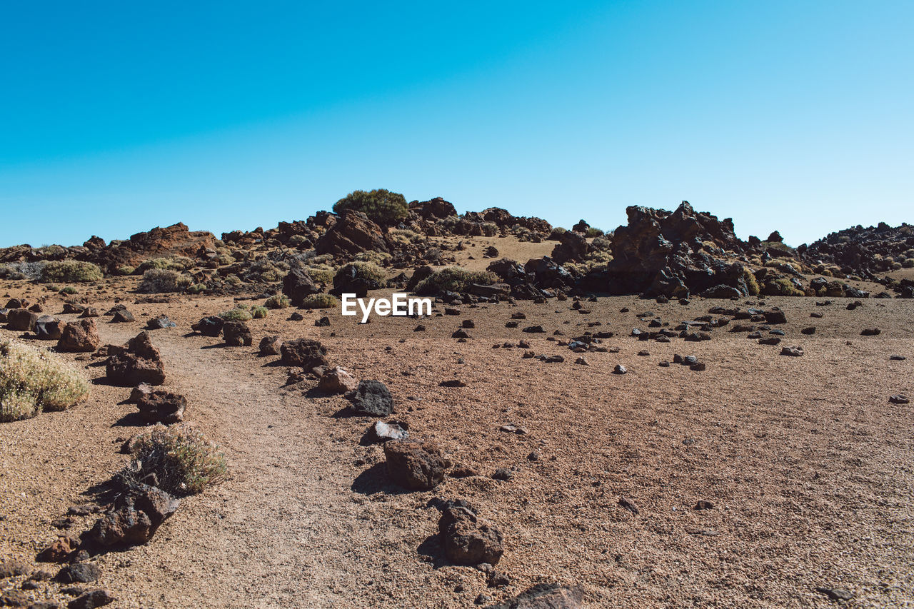 Rocks on land against clear blue sky