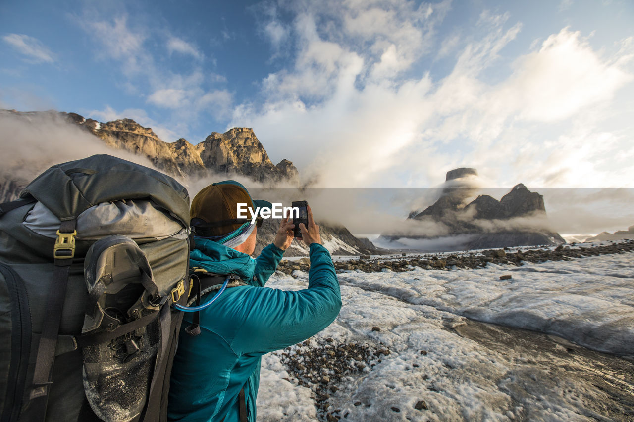 Backpacker uses smartphone to take a photo of mount asgard.