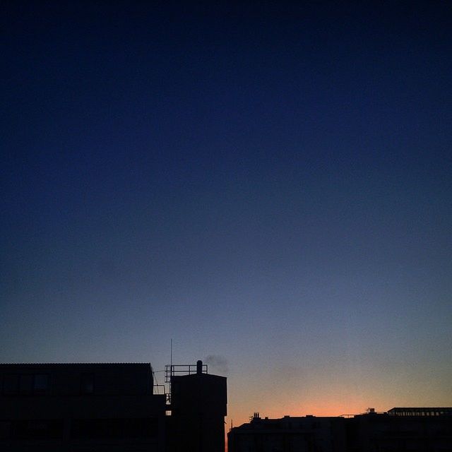 LOW ANGLE VIEW OF BUILDINGS AGAINST CLEAR SKY AT SUNSET