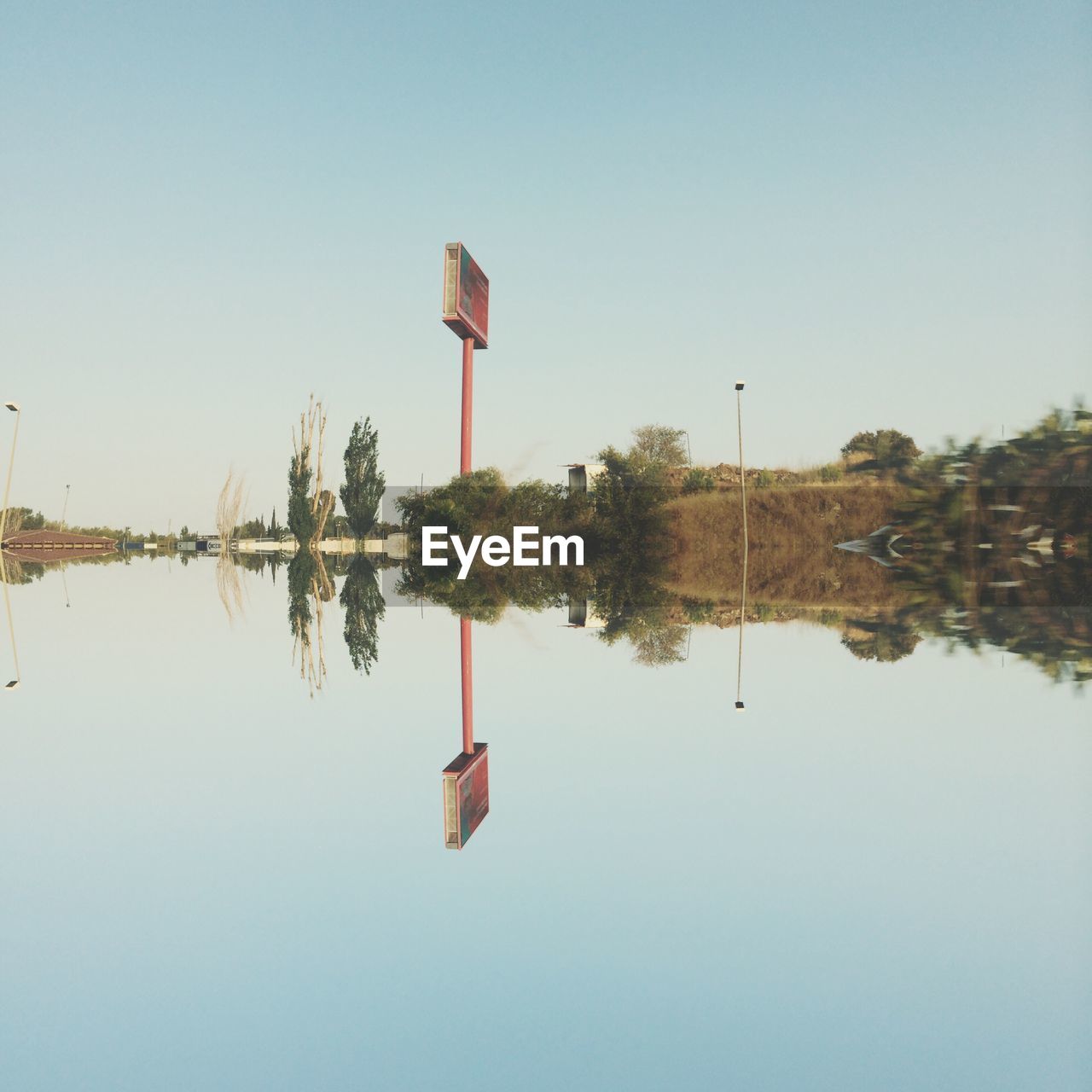 Reflection of signboard on lake against clear sky