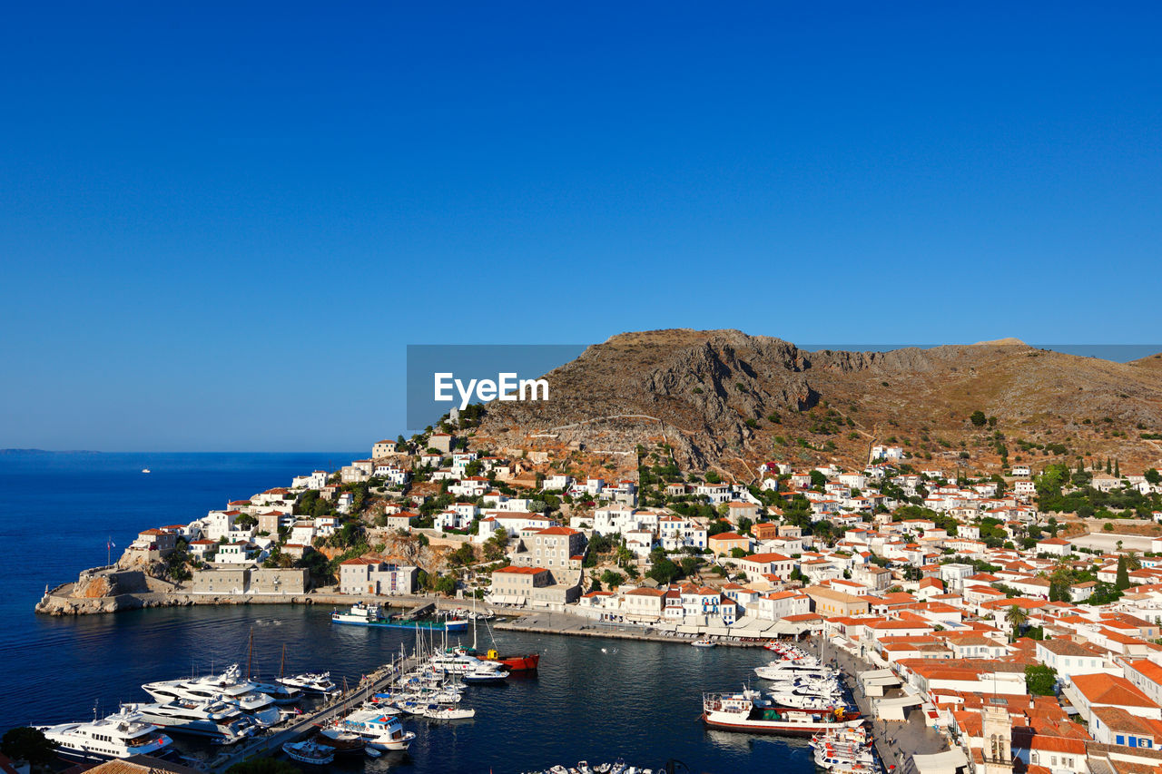 AERIAL VIEW OF SEA AND CITYSCAPE AGAINST BLUE SKY