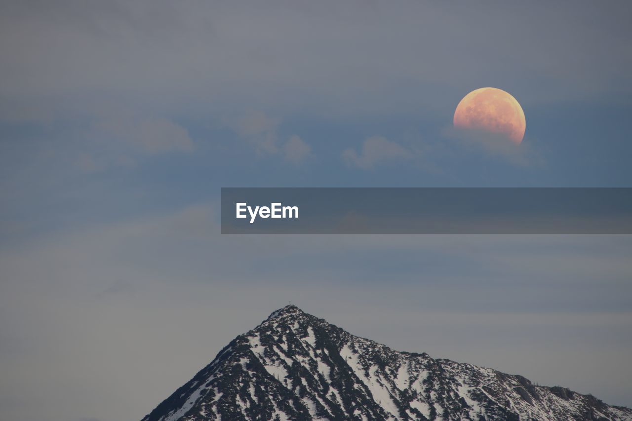 Low angle view of snowcapped mountain against sky at sunset