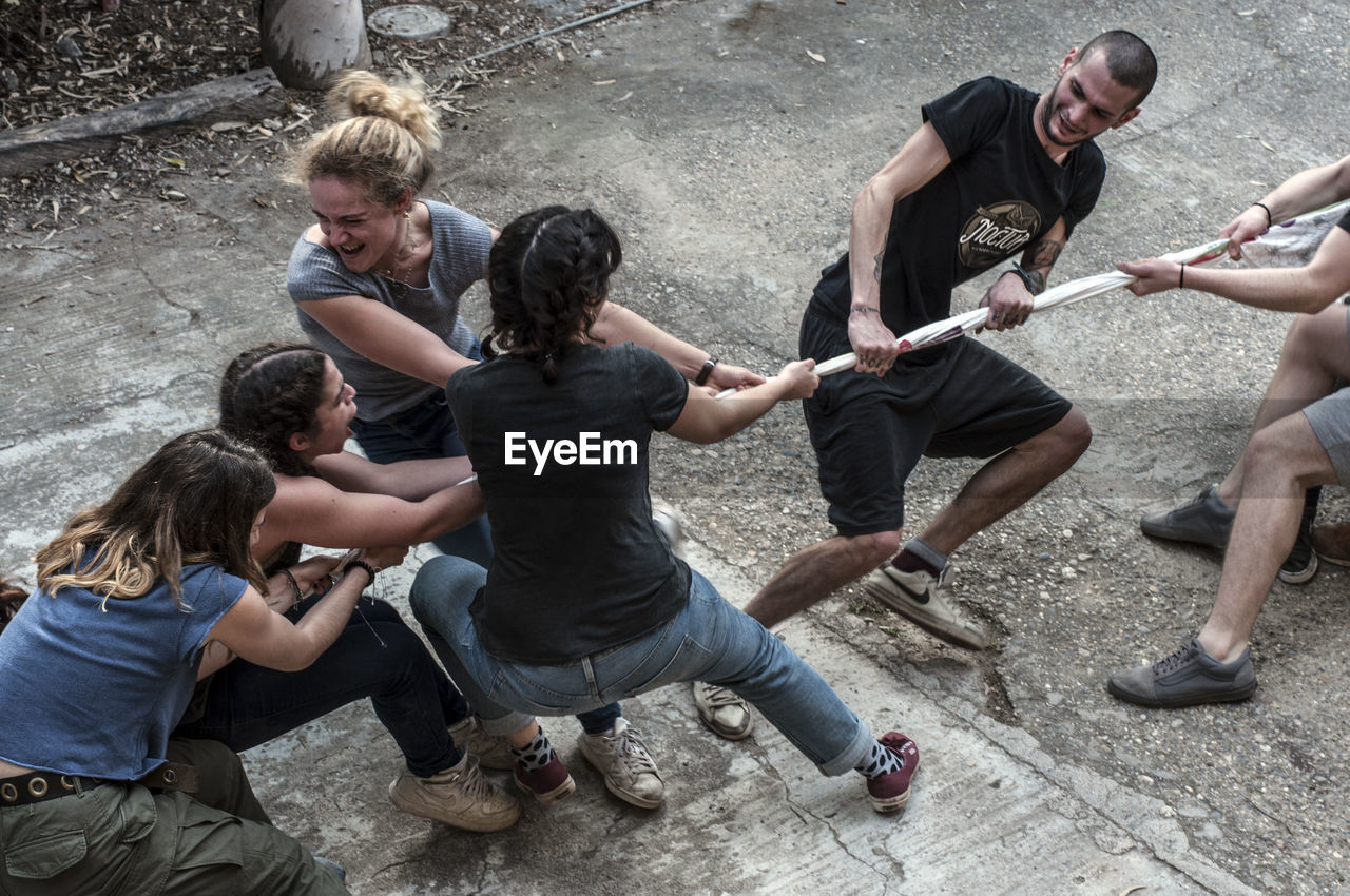 High angle view of friends playing tug-of-war on street