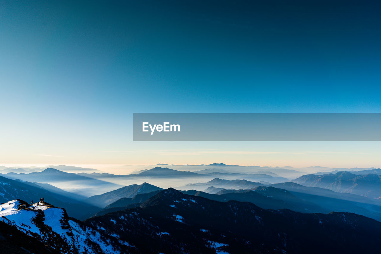 Scenic view of snowcapped mountains against clear blue sky