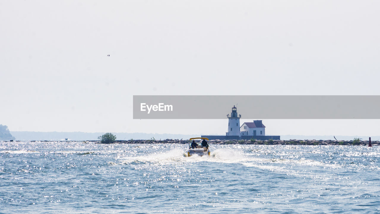 PEOPLE ON BOAT IN SEA AGAINST CLEAR SKY